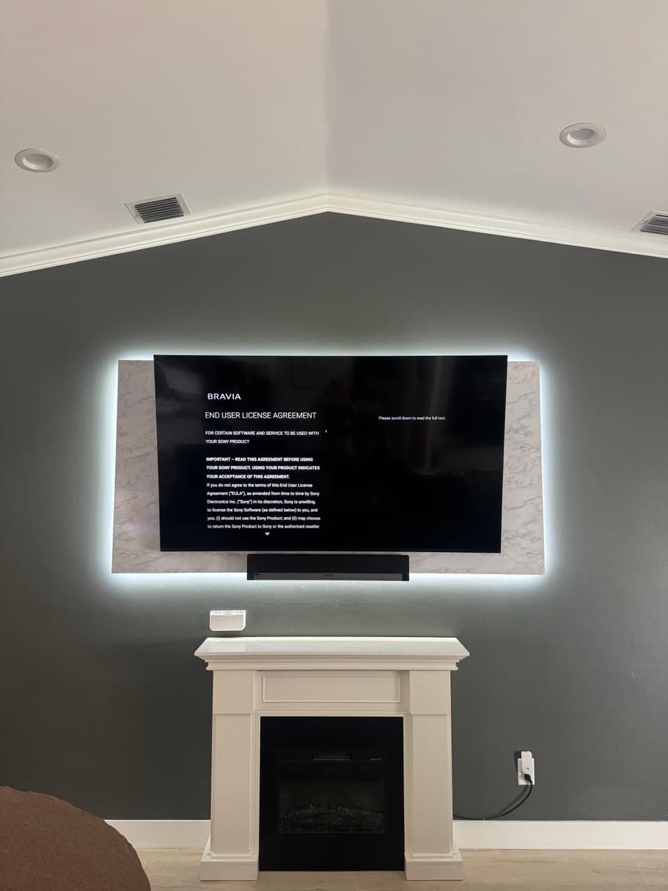 Sony Bravia above the fireplace in Royal Palm Beach — marble wall, soundbar, zero visible cables